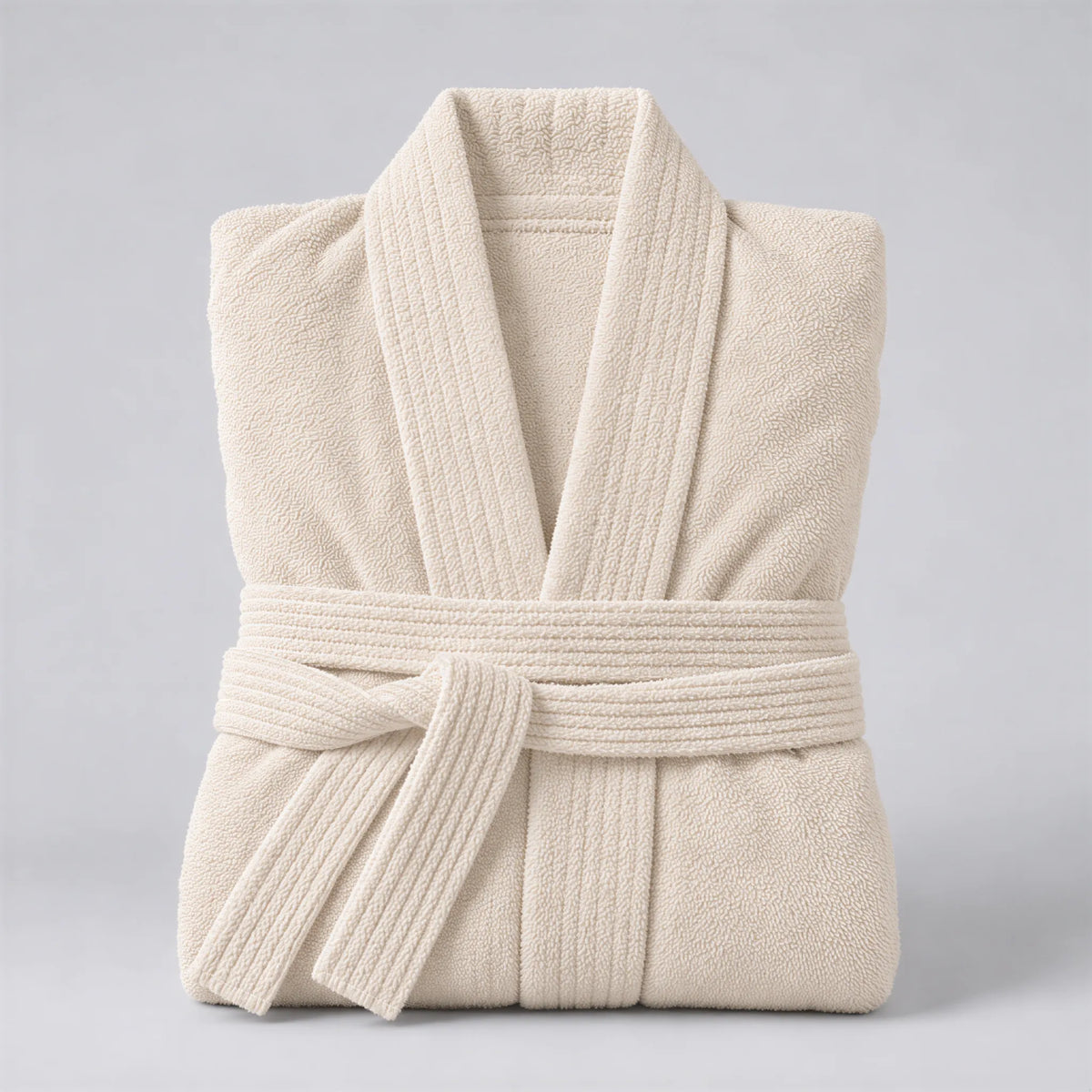 Bademantel creme beige aus Walkfrottee in Kimono-Form, gefaltet auf hellgrauem Hintergrund