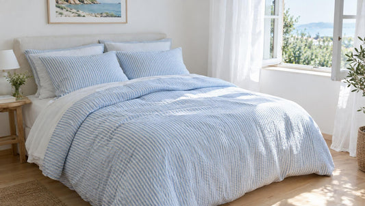 Doppelbett mit weiß-hellblau gestreifter Seersucker-Bettwäsche in einem hellen Sommerschlafzimmer