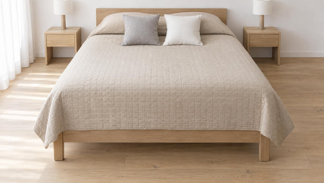 Gesteppte Tagesdecke in Sandbeige auf einem Doppelbett aus hellem Holz