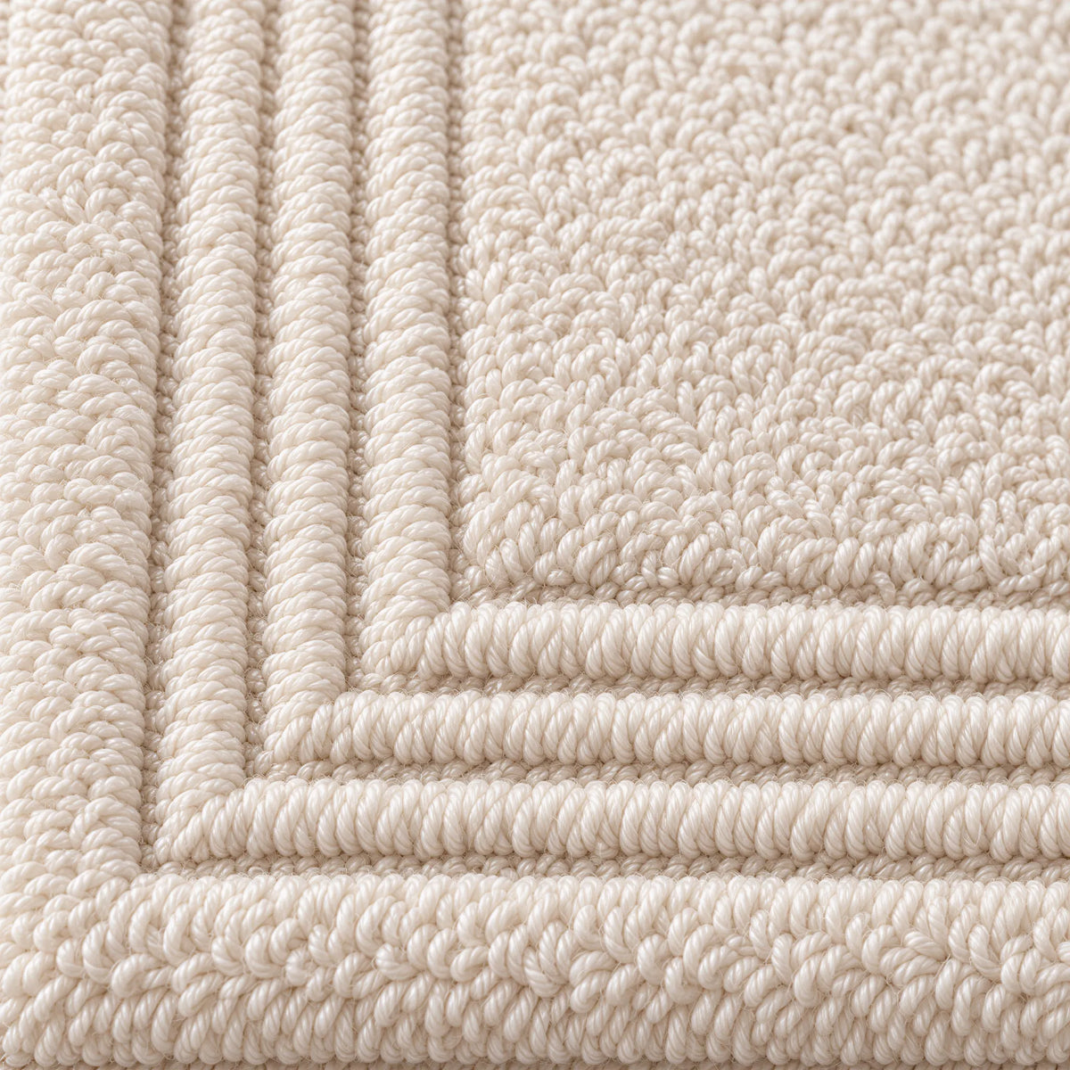 Nahaufnahme der festen Zwirnfrottee-Schlingen mit Stäbchenbordüre – Badematte creme beige