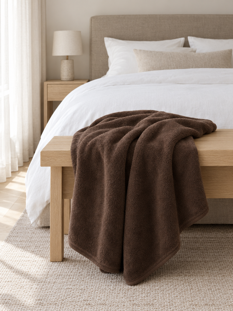 Braune Kuscheldecke über einer hellen Eichenbank im Schlafzimmer
