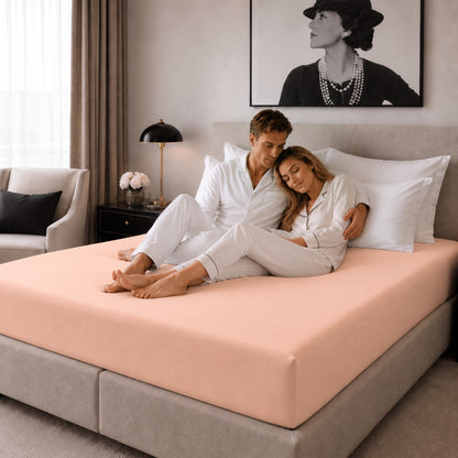 Paar im Schlafzimmer auf einem Bett mit bügelfreiem Spannbettlaken in apricot